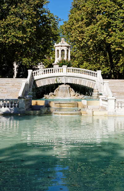 Pont en pierre et fontaine du Jardin Darcy à Dijon dans un parc verdoyant