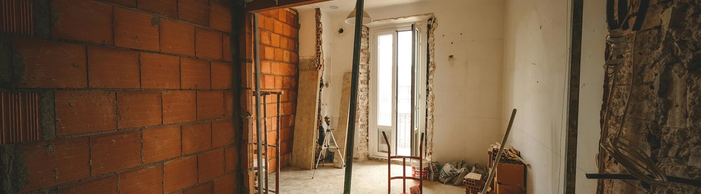 Pièce en rénovation avec mur en briques apparentes et porte-fenêtre sur balcon